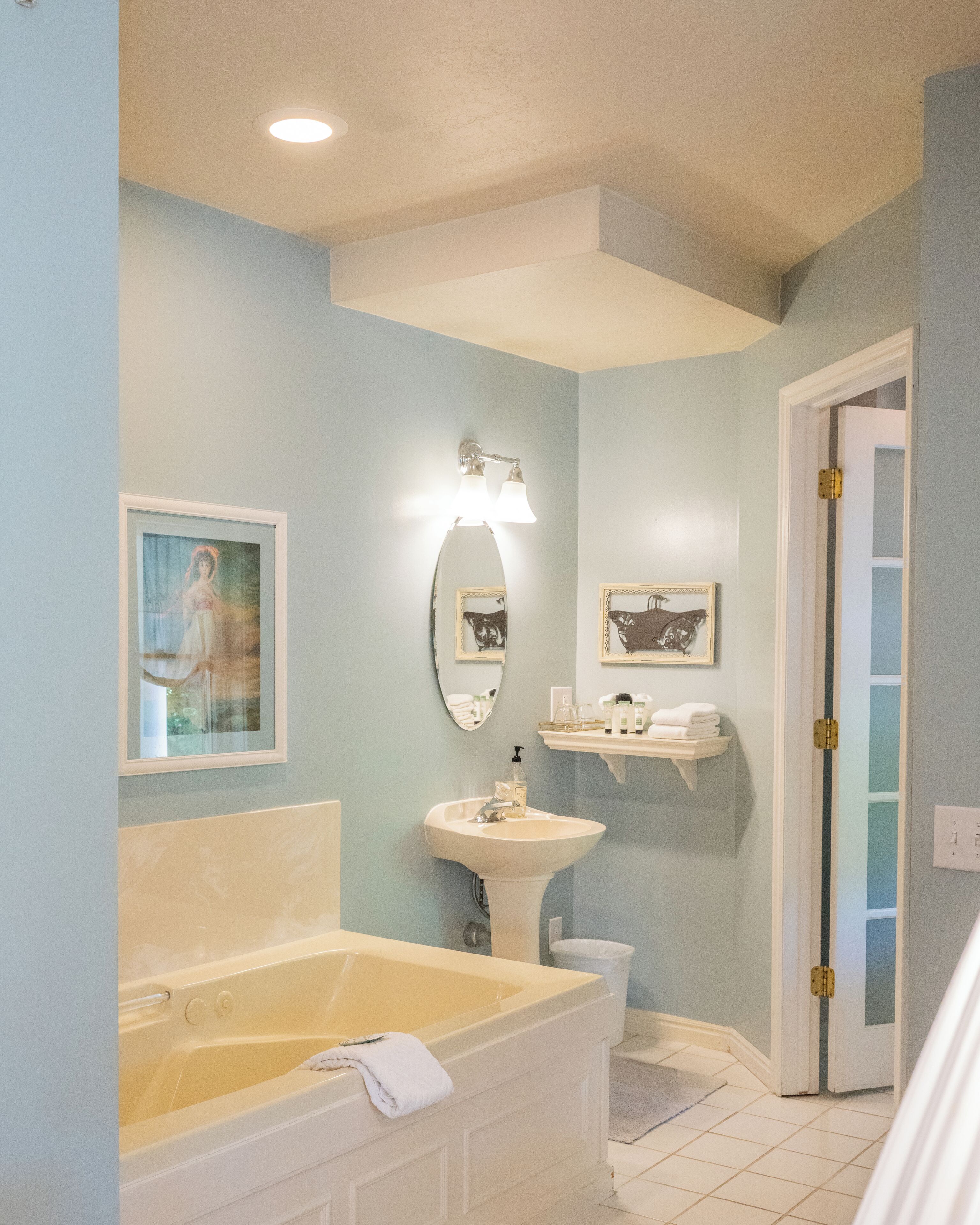 A bathroom with a bathtub, sink, and two framed pictures on the wall.