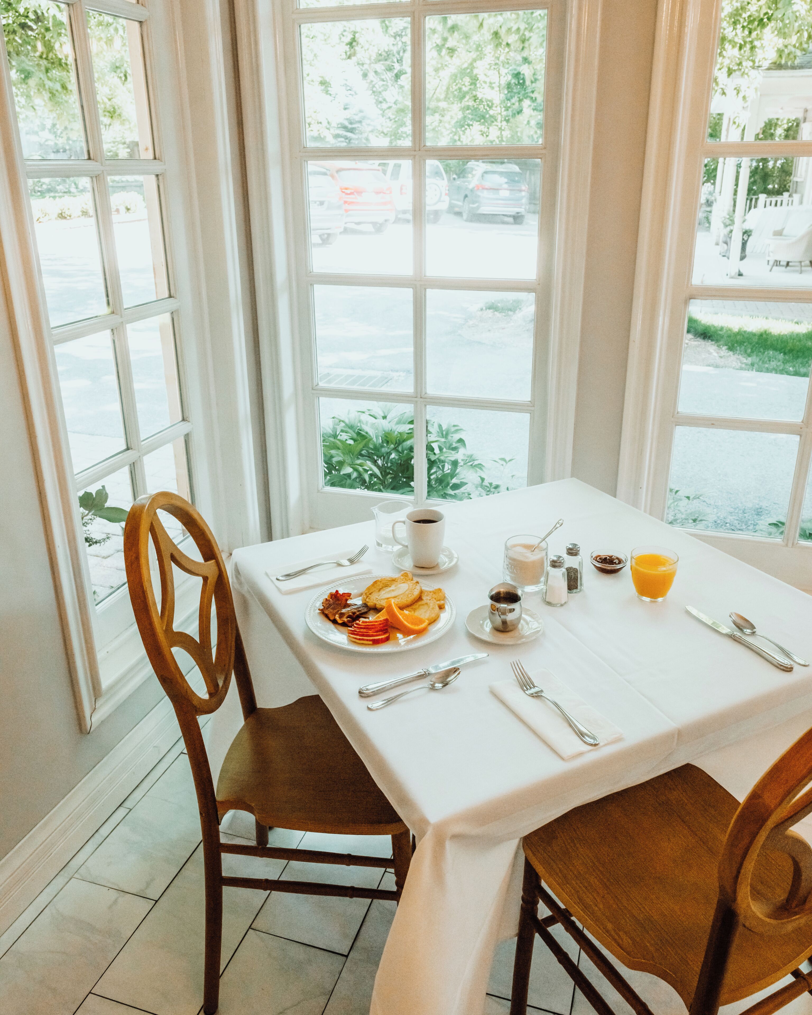 A dining table with a white tablecloth, set with plates, cutlery, and a pitcher of orange juice.
