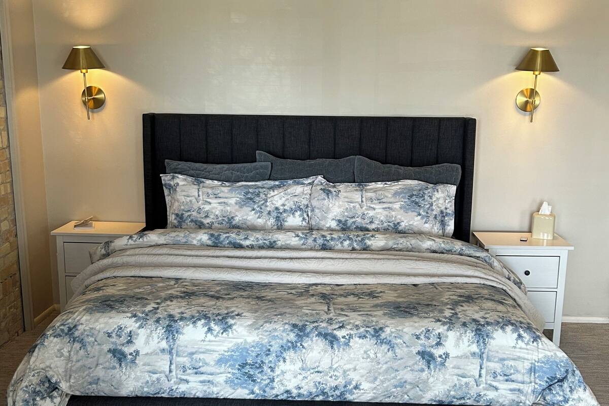 A bed with a dark headboard, two bedside tables with lamps, and a patterned bedspread.