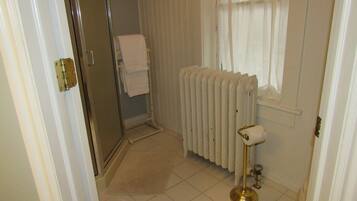 Un baño con un radiador blanco, un perchero y una puerta de ducha.