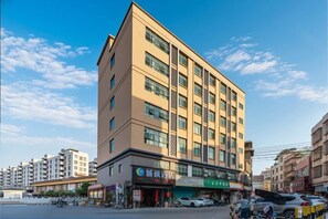 Un hôtel à plusieurs étages au design moderne, doté d’un restaurant situé au rez-de-chaussée et d’une entrée bien visible.