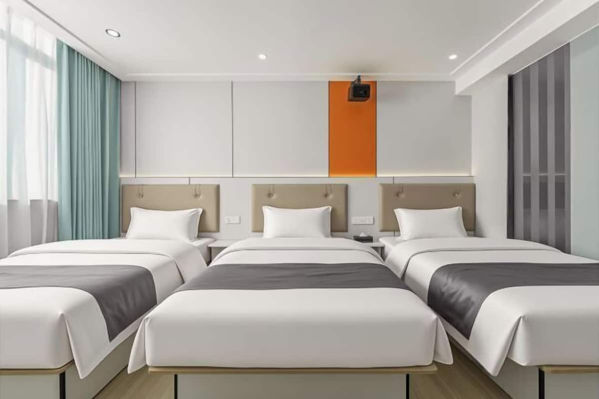 A hotel room with three beds, a large window with curtains, a wall-mounted projector, and a modern design.