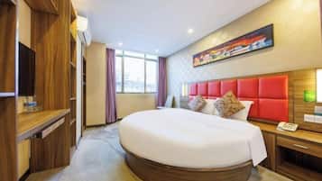 Una habitación de hotel con una cama grande, muebles de madera, un cuadro en la pared y una ventana con cortinas.