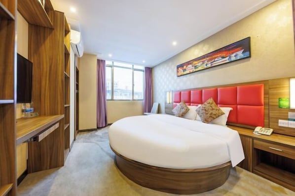 A hotel room with a large bed, wooden furniture, a painting on the wall, and a window with curtains.