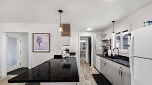 Une cuisine moderne avec un îlot central doté d’un plan de travail noir, des armoires blanches et un plancher en bois.
