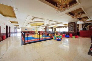 A spacious lobby with a play area, a reception desk, and a chandelier.