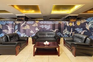 A room with three black leather sofas arranged around a central wooden coffee table. - Lia Daocheng Resort (Daocheng County)