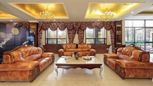 A room with a sofa set, a coffee table, and a large painting on the wall. - Lia Daocheng Resort (Daocheng County)