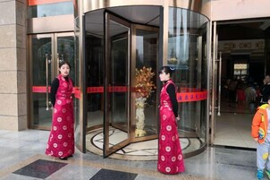 A revolving door entrance with a glass door and a red stripe.