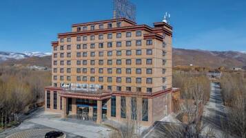 A multi-story hotel with a central entrance and a parking area.