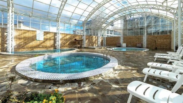 An indoor swimming pool with clear glass ceilings, lounge chairs, and a stone floor. - Lia Daocheng Resort (Daocheng County)