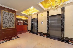 A hotel lobby with a reception desk, elevators, and a chandelier. - Lia Daocheng Resort (Daocheng County)