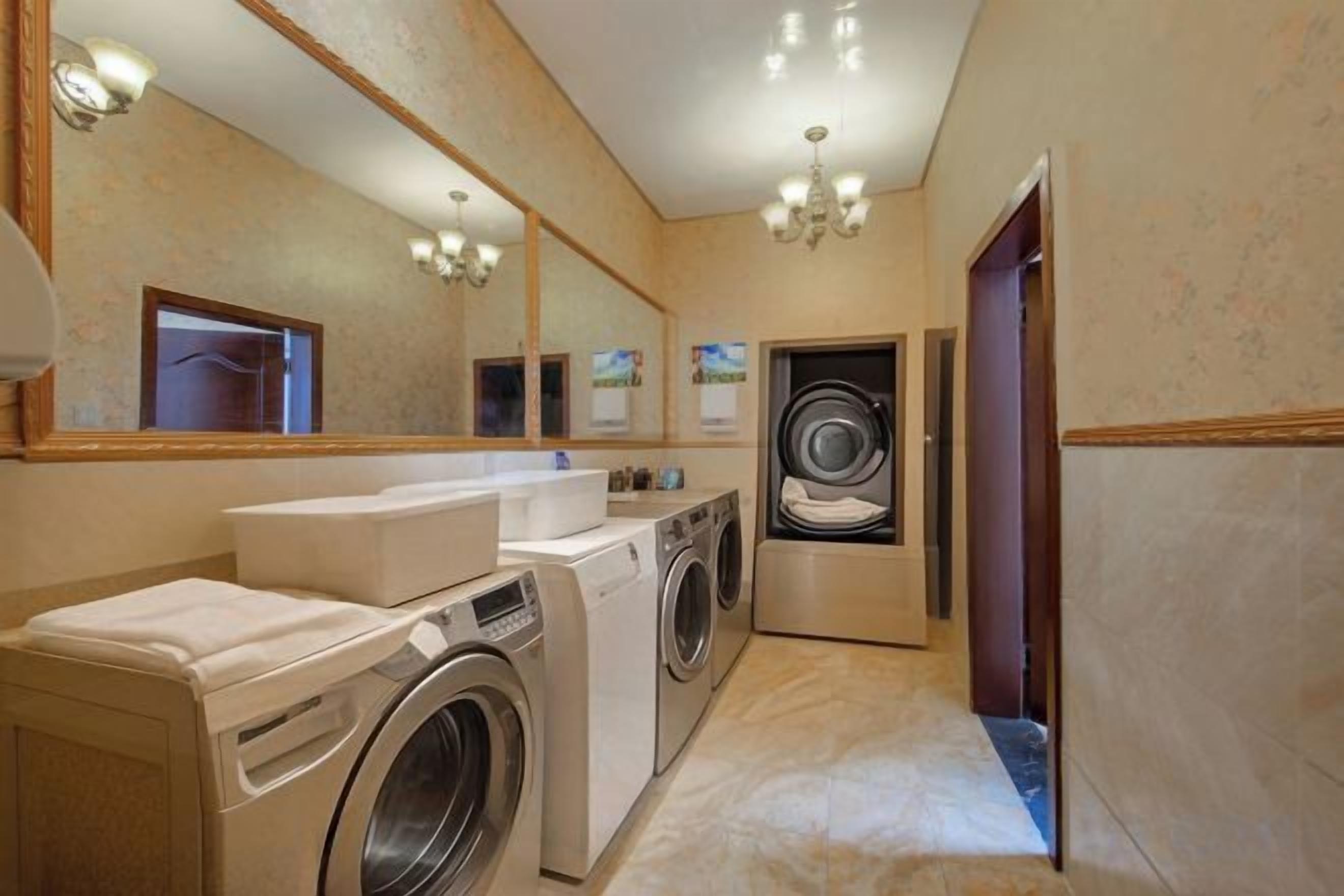 Une salle de bain d’hôtel équipée d’un lave-linge, d’un lavabo et d’un miroir.