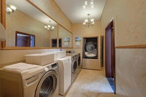 A hotel bathroom with a washing machine, a sink, and a mirror. - Lia Daocheng Resort (Daocheng County)