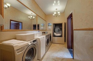 Un baño de hotel con lavadora, lavamanos y espejo.