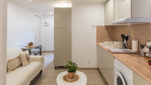 Et moderne køkken med vaskemaskine, et spiseområde med bord og stole samt en opholdsstue med sofa.