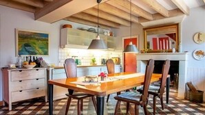 Ein Essbereich mit Holztisch und -stühlen, einer hängenden Leuchte und einem gefliesten Boden.