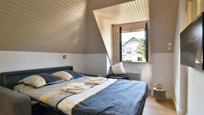 Un dormitorio con cama, ventana y televisor.