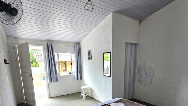 A bedroom with a bed, a small stool, and a door leading to an outdoor area.