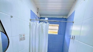 A small, narrow bathroom with white and blue tiles, a white sink, a toilet, and a shower curtain.