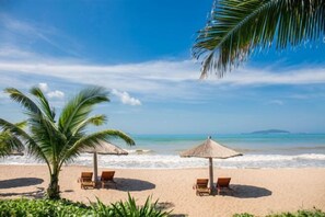 A beach with palm trees, beach chairs, and thatched umbrellas. - Yinyun Seaview Hotel (Sanya)