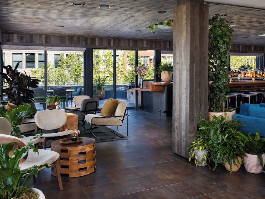 A spacious outdoor seating area with wooden furniture, potted plants, and a bar counter.