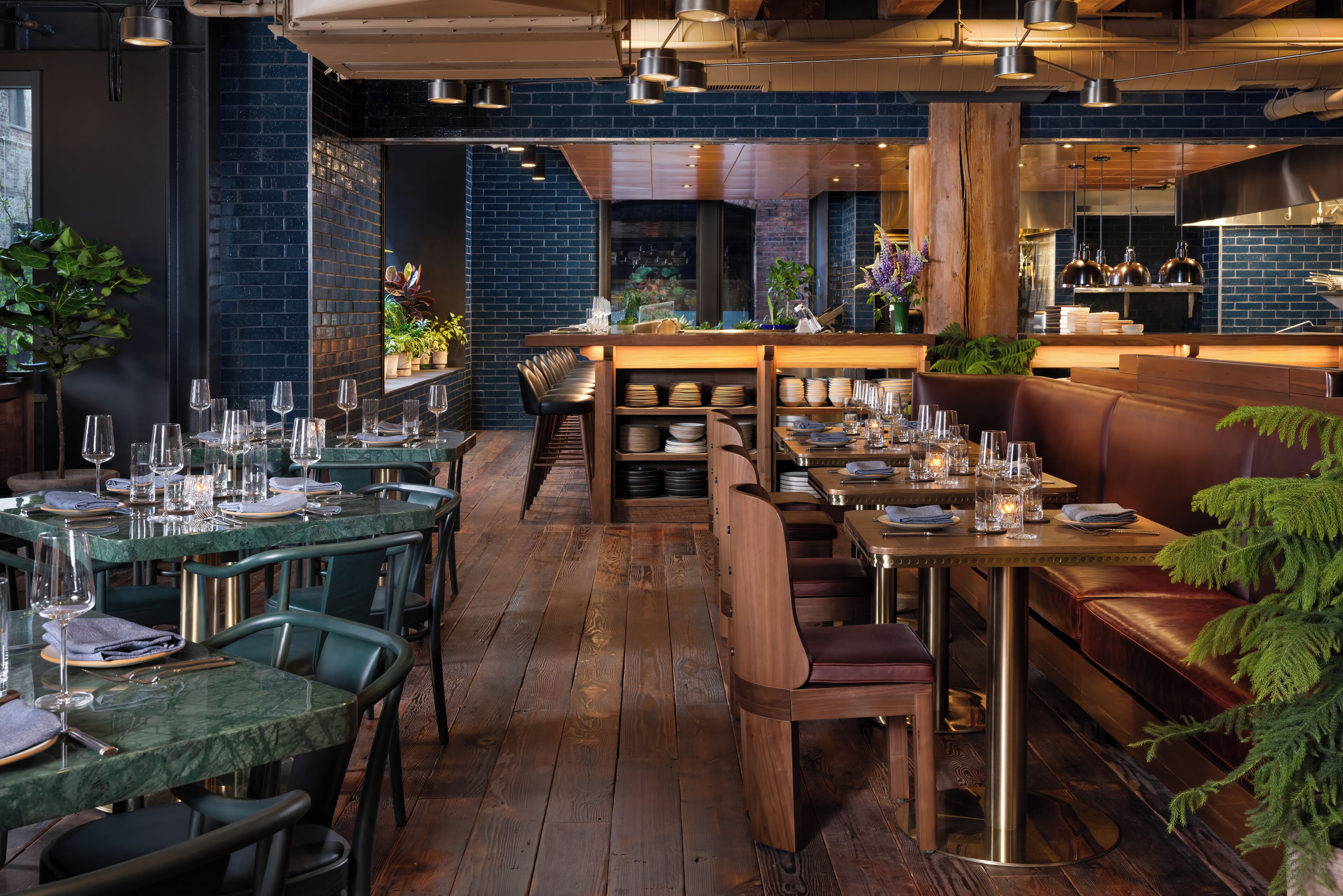 A restaurant interior with wooden tables, green chairs, and a bar area.