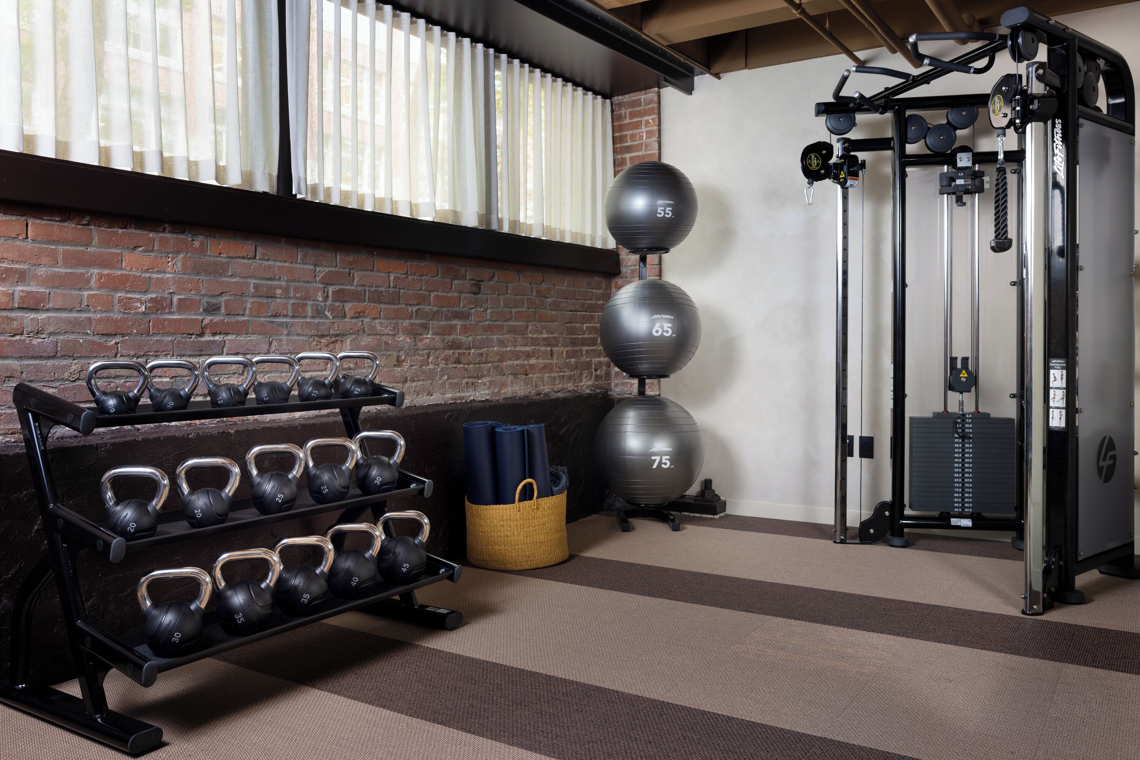 A gym with kettlebells, exercise balls, and a squat rack.