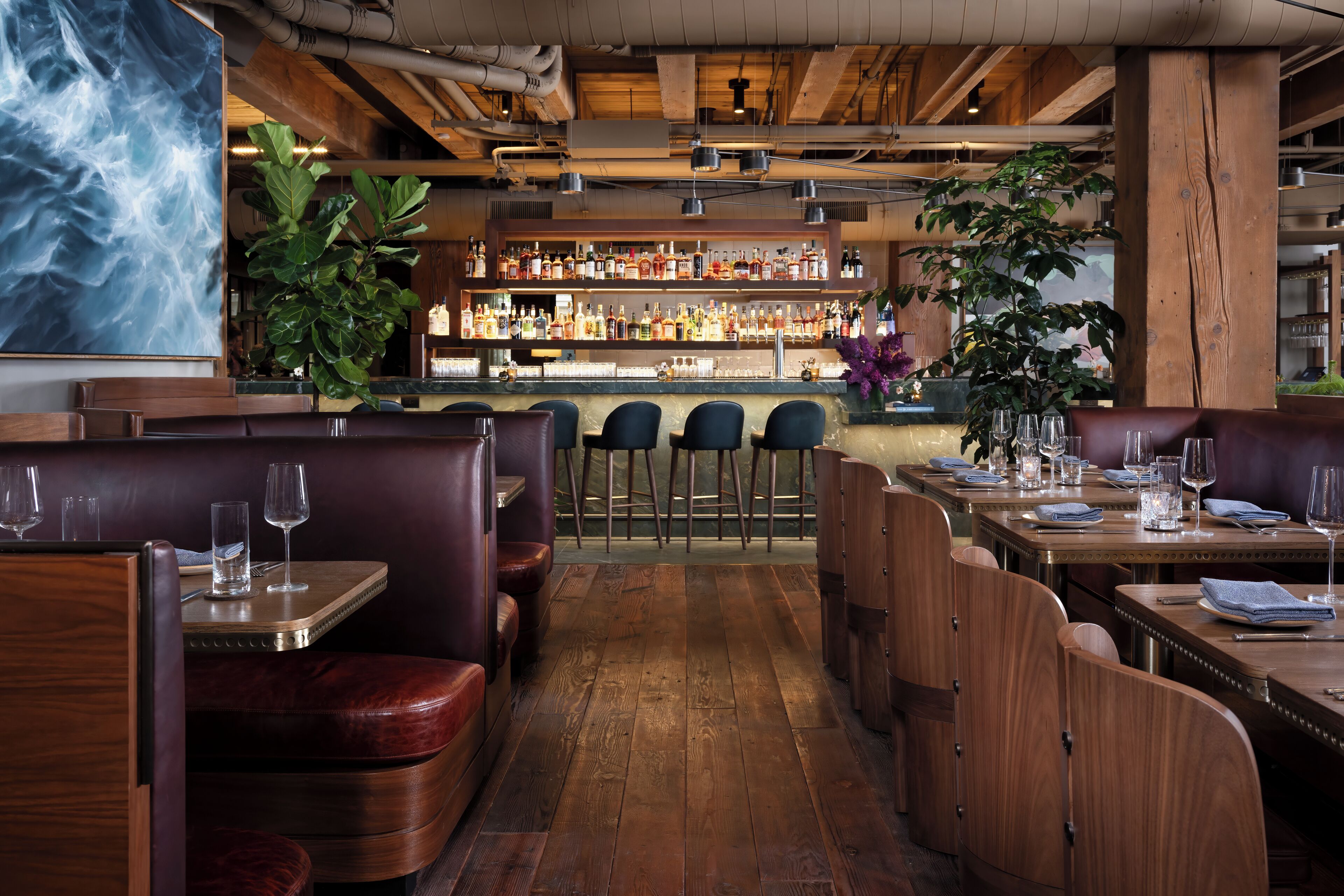 Interior de un restaurante con cabinas de madera, zona de bar y una variedad de botellas en estanterías.