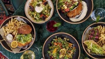 A table with various dishes including salads, fries, and a burger.