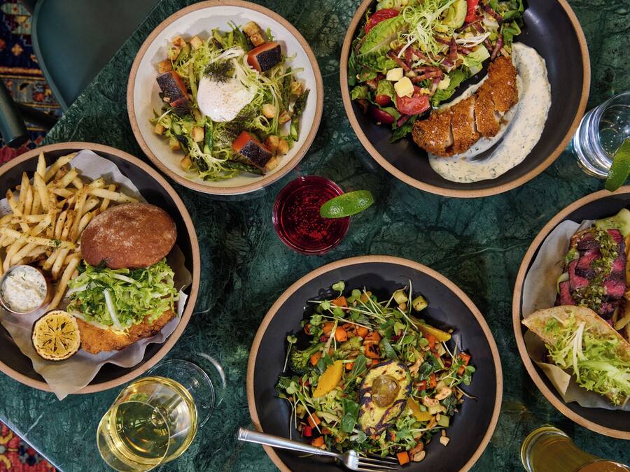 A table with various dishes including salads, fries, and a burger.