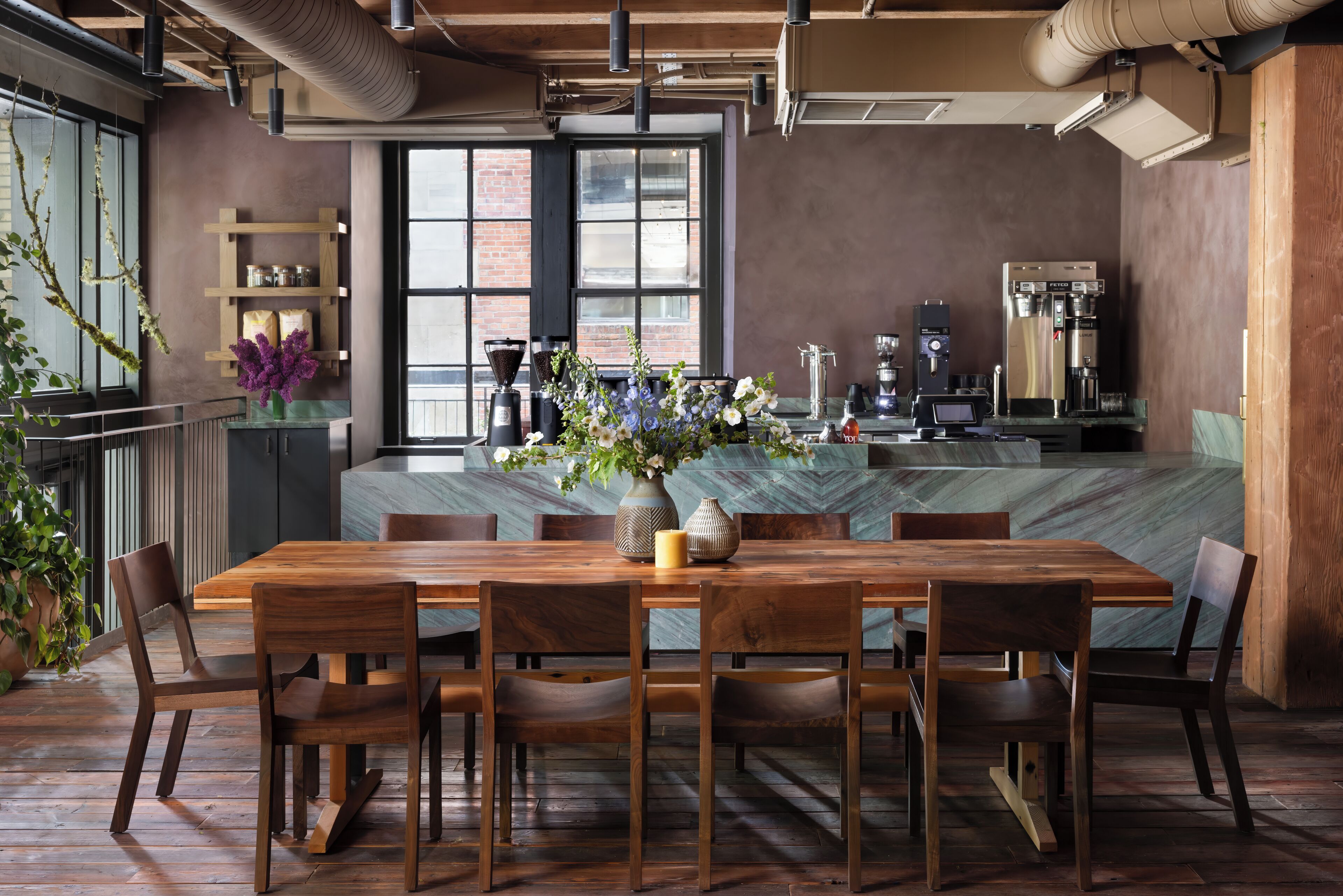 Un comedor moderno con mesa y sillas de madera, una isla de mármol y una cafetera.