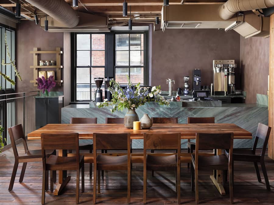 Un comedor moderno con mesa y sillas de madera, una isla de mármol y una cafetera.