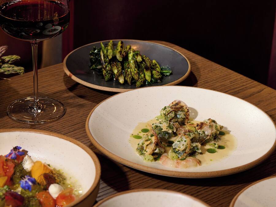 A dining table with various dishes and a glass of red wine.