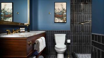 A bathroom with a wooden vanity, a white toilet, and a shower area.