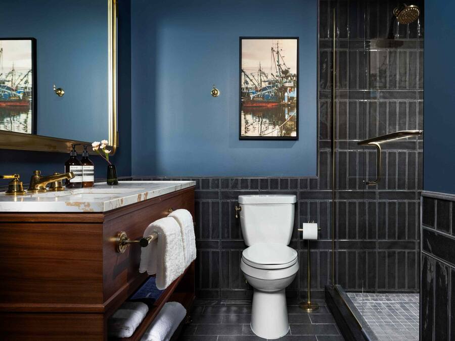 A bathroom with a wooden vanity, a white toilet, and a shower area.