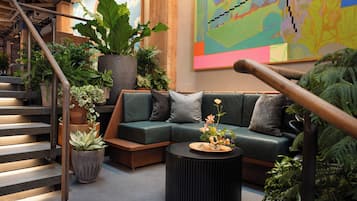 Ein modernes Wohnzimmer mit einem grünen Sofa, einem runden schwarzen Couchtisch und einer Treppe mit Metallgeländern.