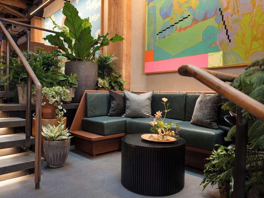 Ein modernes Wohnzimmer mit einem grünen Sofa, einem runden schwarzen Couchtisch und einer Treppe mit Metallgeländern.
