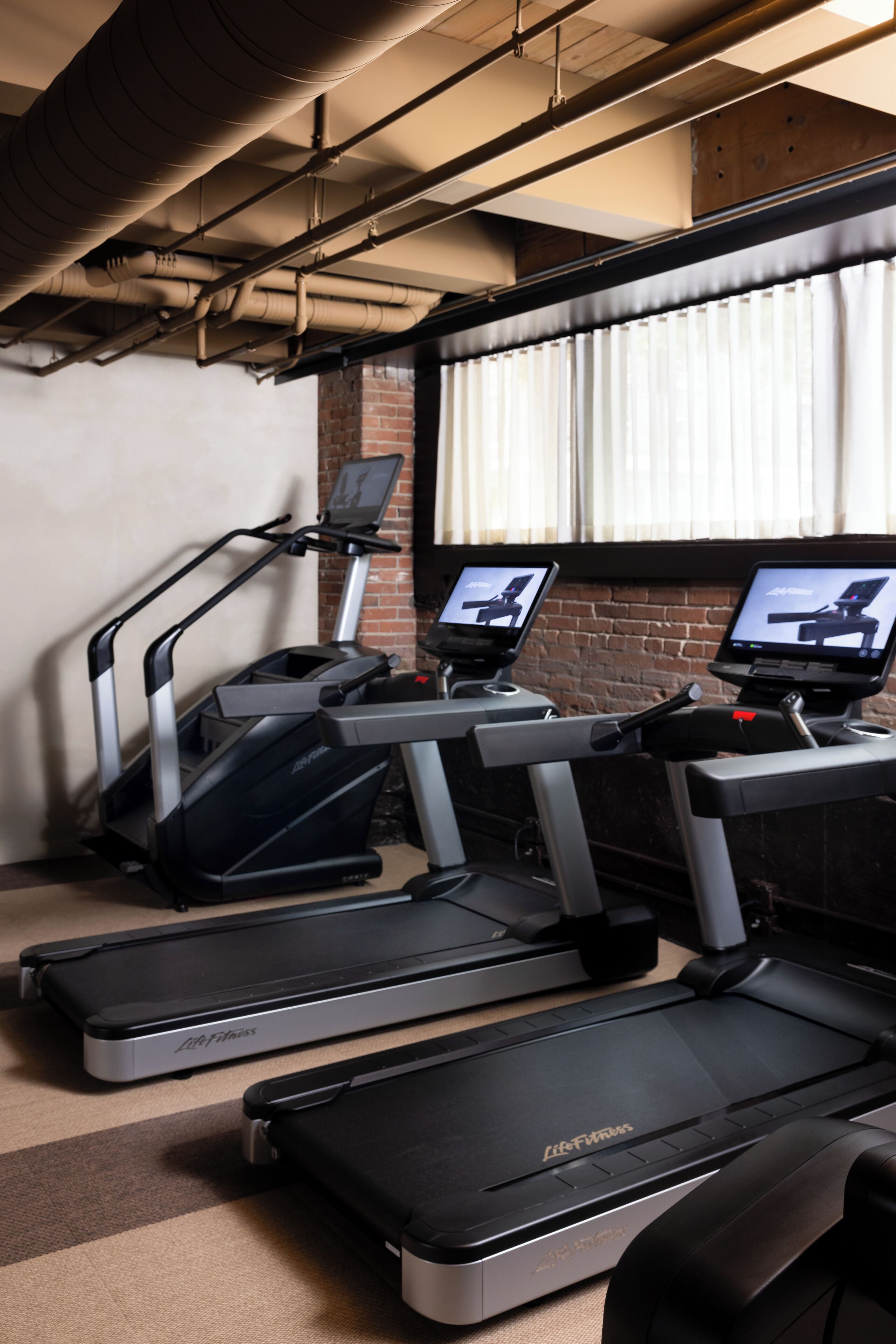 A gym with treadmills, a stationary bike, and a rowing machine.