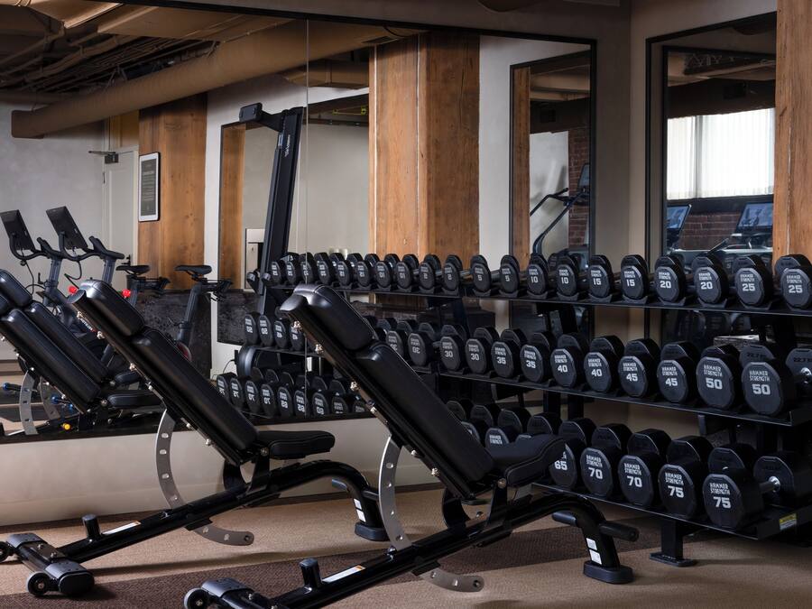 Un gimnasio con equipo de ejercicio, incluyendo cintas de correr y mancuernas.