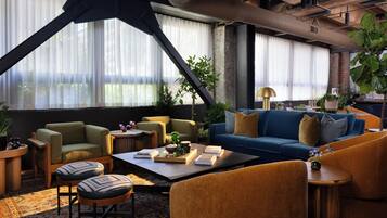 Un salon moderne avec un canapé bleu, un fauteuil vert et une table basse agrémentée de livres et d’objets décoratifs.