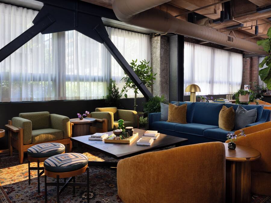 Ein modernes Wohnzimmer mit einem blauen Sofa, einem grünen Sessel und einem Couchtisch mit Büchern und Dekoration.