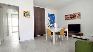 A modern living room with a dining area, a TV, and artwork on the walls. - Casa Golden - A Due Passi Dalle Spiagge Di Pescoluse (Pescoluse)