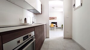 A modern kitchen with dark wooden cabinets, stainless steel appliances, and a white countertop. - Casa Golden - A Due Passi Dalle Spiagge Di Pescoluse (Pescoluse)