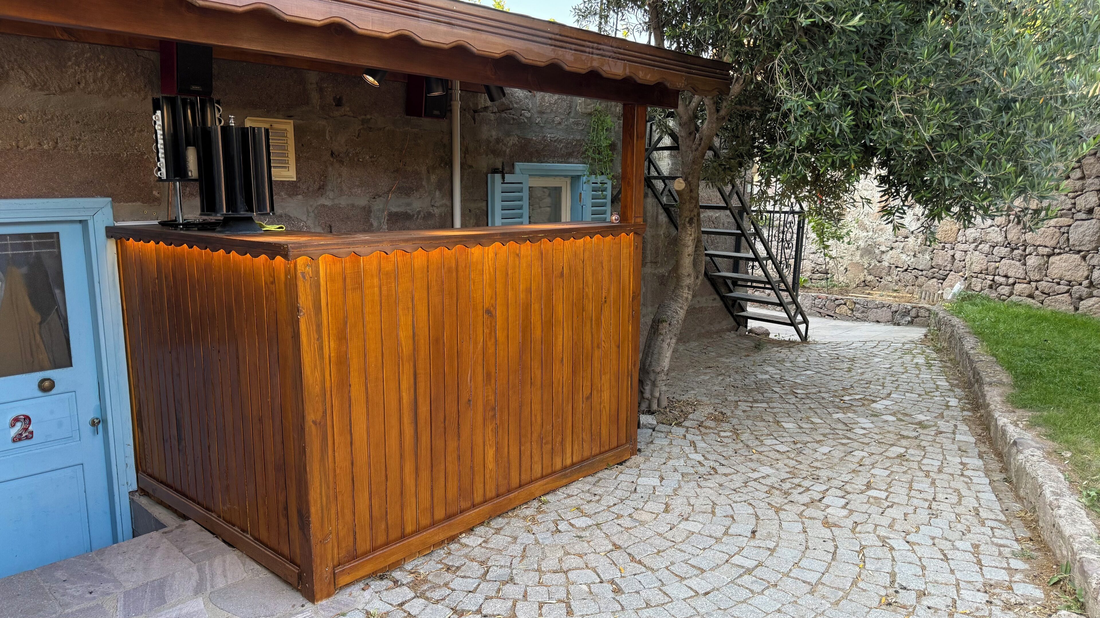 A rustic wooden bar with a blue door and a stone wall backdrop.