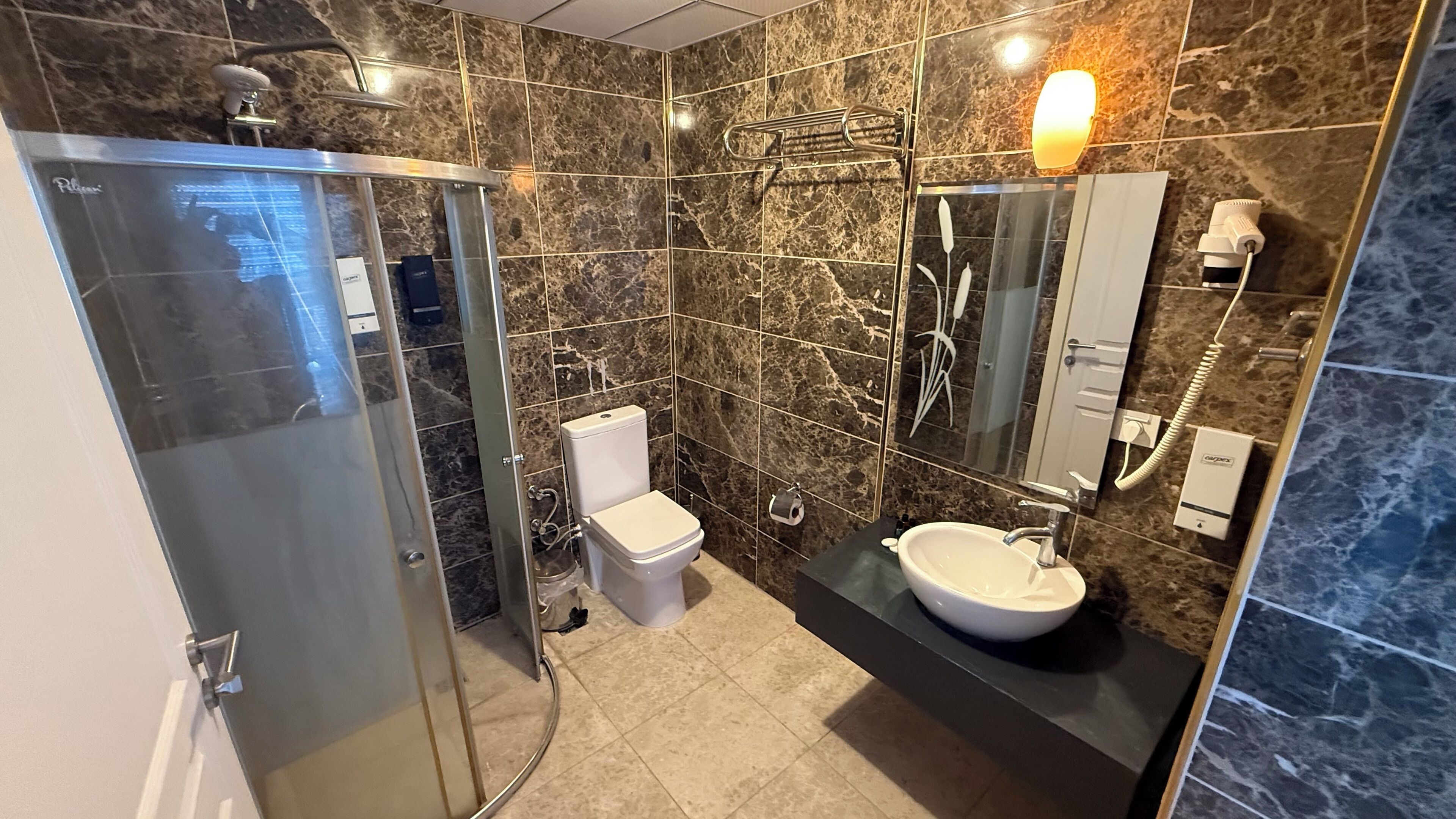 Een moderne badkamer met een douchecabine, een toilet en een wastafel met spiegel erboven.