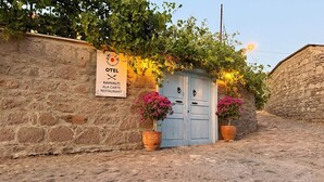 A stone wall with a sign for a restaurant named "Kahvalti Ala Carte Restaurant" and a blue door with two potted plants.