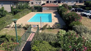 A swimming pool surrounded by greenery, with a building in the background.