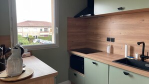 A modern kitchen with a wooden countertop, a built-in stove, a black sink, and a window overlooking a residential area.