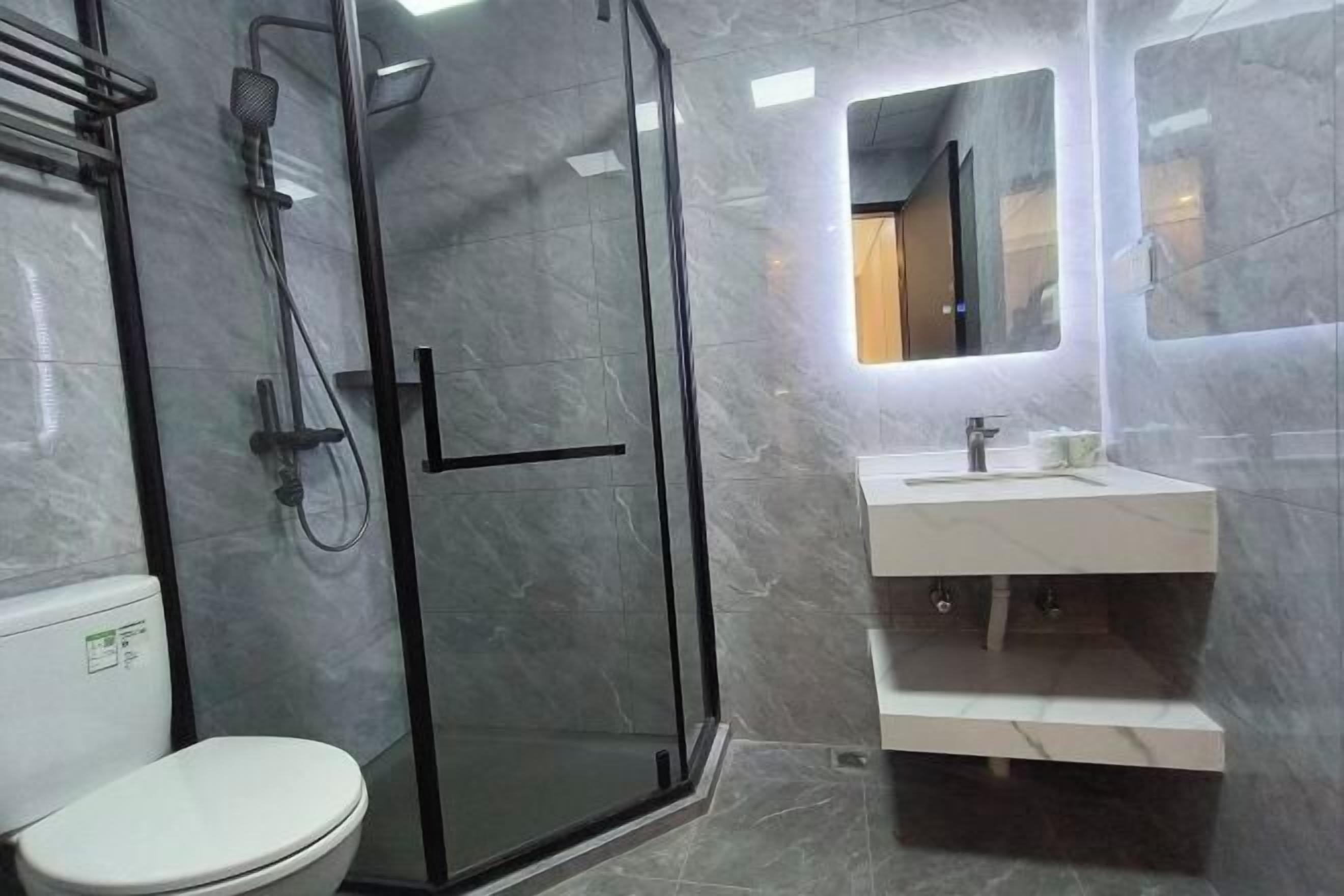 Un baño con ducha de vidrio, inodoro blanco y tocador con espejo.